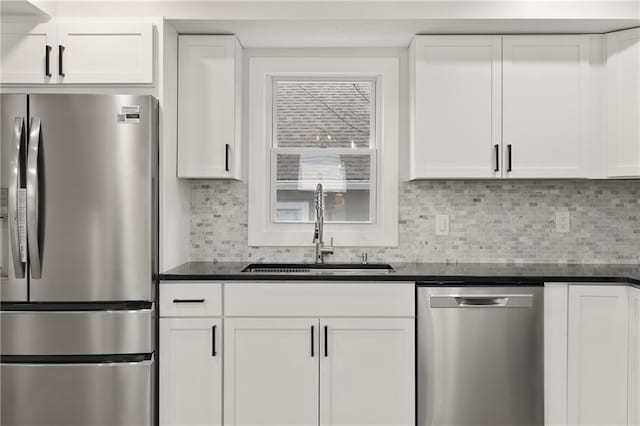 kitchen featuring dark countertops, tasteful backsplash, appliances with stainless steel finishes, and a sink