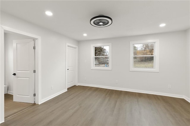 unfurnished bedroom featuring baseboards, wood finished floors, and recessed lighting