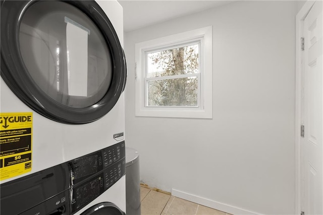 laundry area with laundry area, stacked washer and clothes dryer, baseboards, and light tile patterned floors