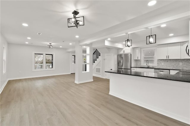 kitchen with light wood-style flooring, appliances with stainless steel finishes, backsplash, and a sink