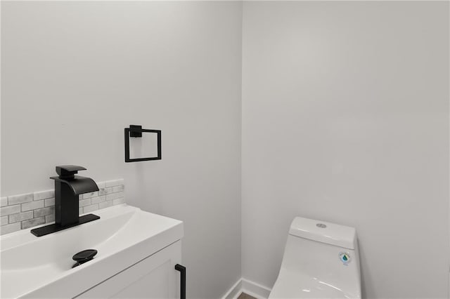 bathroom with baseboards, vanity, toilet, and decorative backsplash