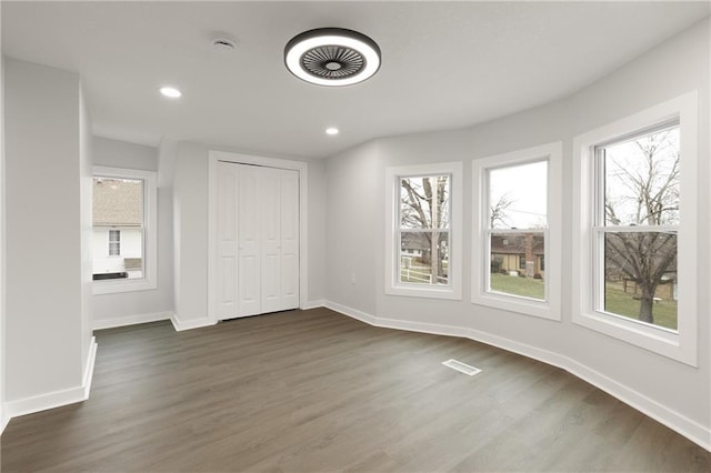 unfurnished bedroom featuring dark wood-style floors, visible vents, and baseboards