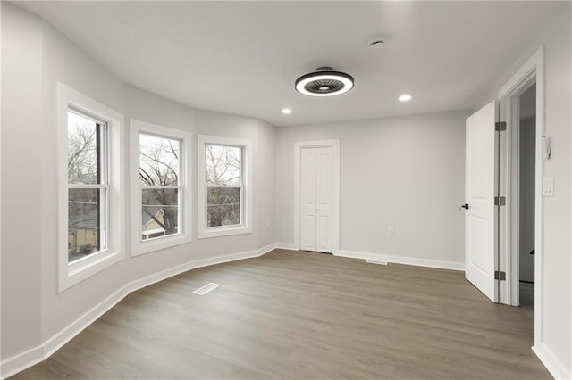 empty room with recessed lighting, visible vents, baseboards, and wood finished floors