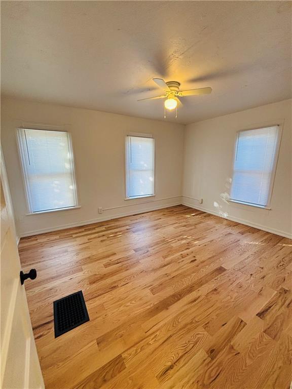 empty room with ceiling fan and light wood-type flooring