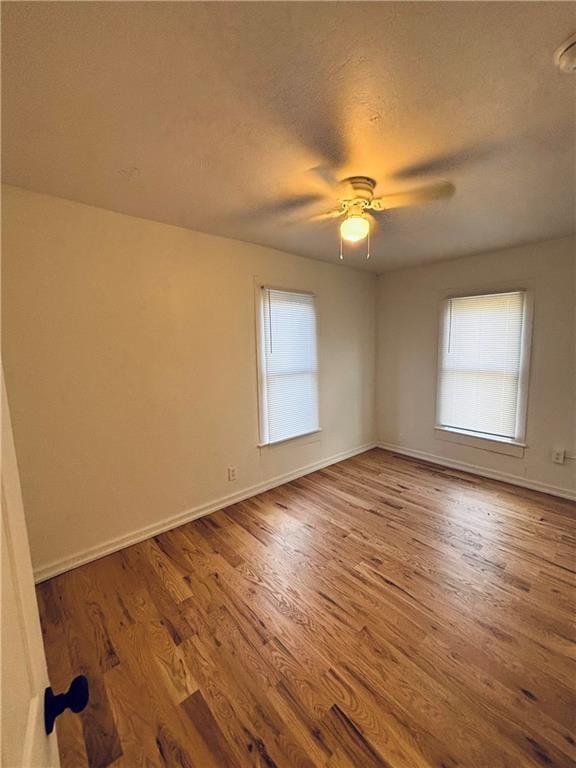 empty room featuring hardwood / wood-style flooring, ceiling fan, a textured ceiling, and a wealth of natural light