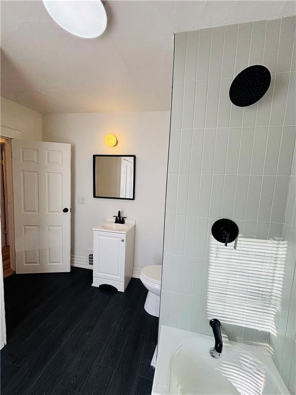 bathroom with vanity, hardwood / wood-style floors, a bathtub, and toilet