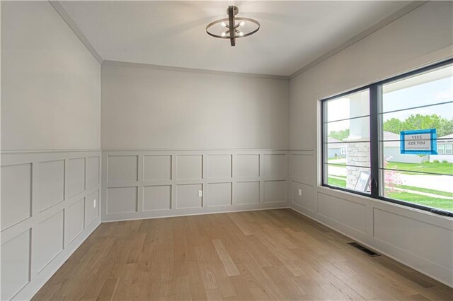2327 Fishing Ln, Kearney, MO 64060 - empty room featuring a decorative wall, light wood finished floors, crown molding, and a wainscoted wall