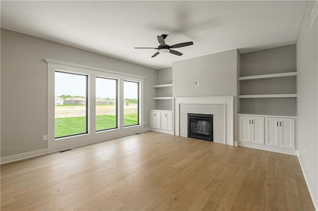 2327 Fishing Ln, Kearney, MO 64060 - unfurnished living room with ceiling fan, a tiled fireplace, built in shelves, and baseboards
