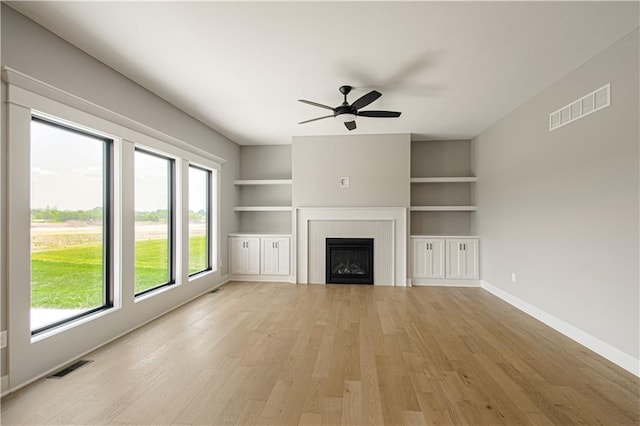 2327 Fishing Ln, Kearney, MO 64060 - unfurnished living room with light wood-type flooring, ceiling fan, baseboards, a fireplace, and built in shelves