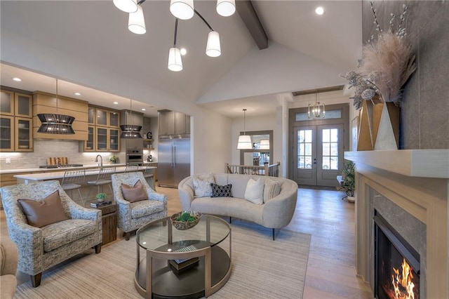 living room featuring high vaulted ceiling, sink, light hardwood / wood-style floors, beam ceiling, and french doors