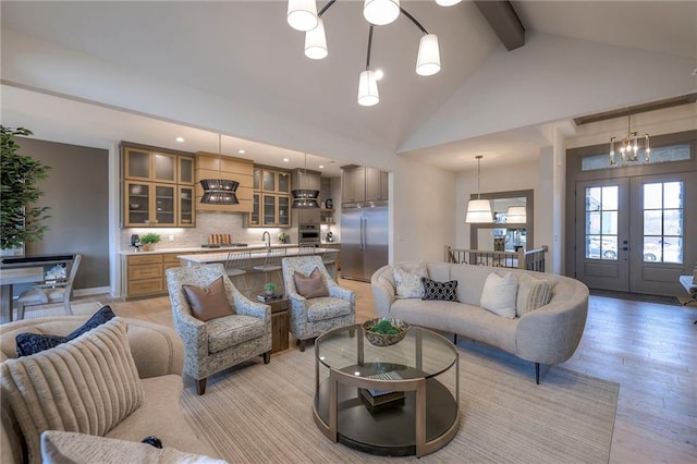 living room featuring beam ceiling, high vaulted ceiling, light hardwood / wood-style floors, french doors, and a chandelier