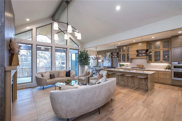 living room featuring an inviting chandelier, high vaulted ceiling, sink, light hardwood / wood-style floors, and beam ceiling