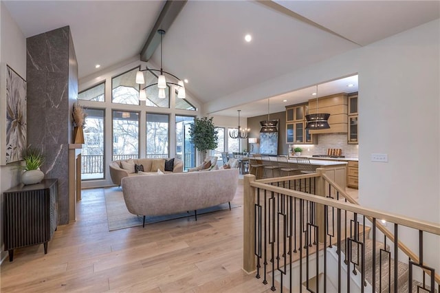 living room with an inviting chandelier, vaulted ceiling with beams, and light hardwood / wood-style floors