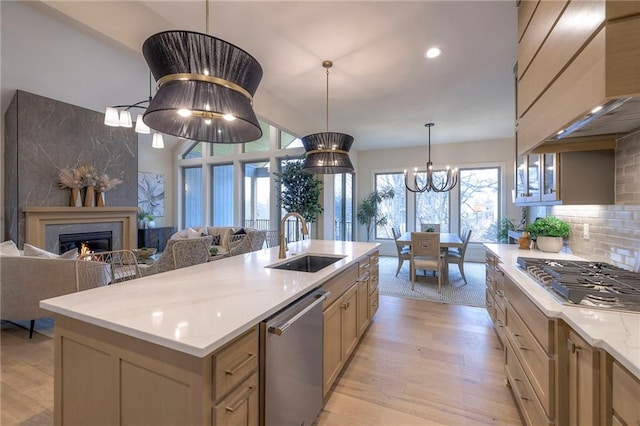 kitchen with an island with sink, sink, decorative backsplash, stainless steel appliances, and custom range hood