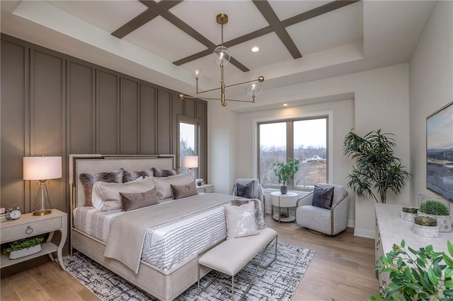 bedroom featuring coffered ceiling, light hardwood / wood-style flooring, and beamed ceiling