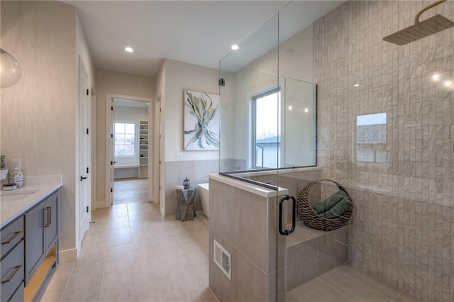 bathroom with vanity, separate shower and tub, tile patterned flooring, and tile walls