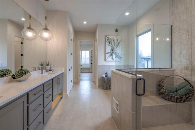 bathroom featuring vanity, a shower with shower door, tile patterned flooring, and tile walls