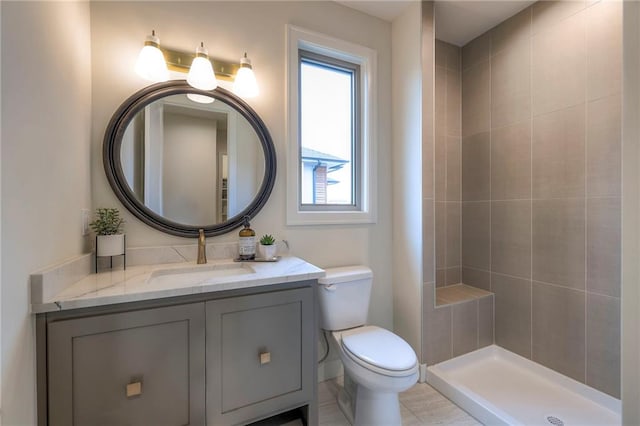 bathroom featuring vanity, tiled shower, and toilet