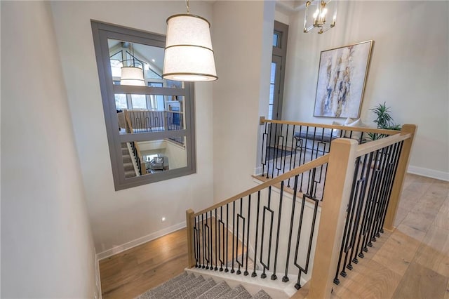 staircase with wood-type flooring and a notable chandelier