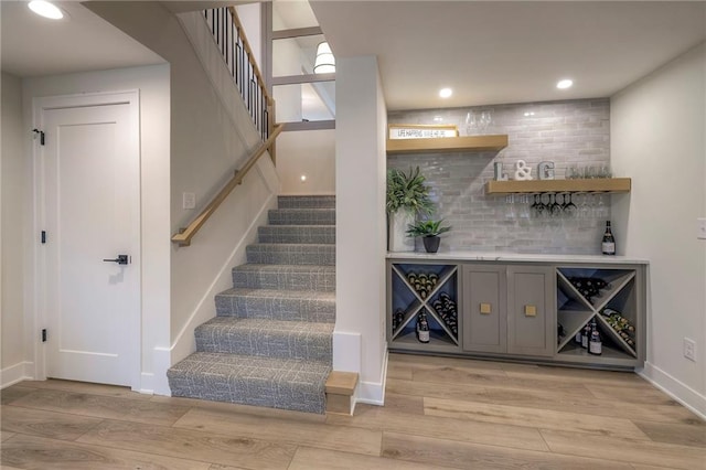 bar with gray cabinets, backsplash, and light hardwood / wood-style flooring