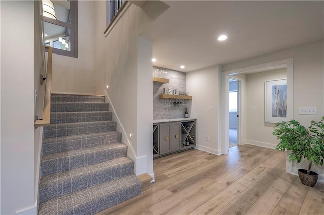 staircase with hardwood / wood-style flooring and bar area