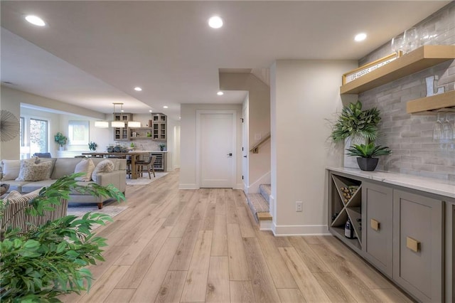 bar with pendant lighting, gray cabinetry, decorative backsplash, and light hardwood / wood-style flooring