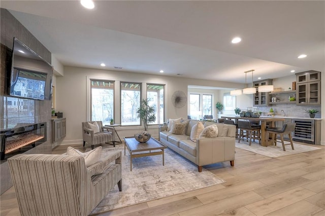 living room featuring a large fireplace, light hardwood / wood-style flooring, and beverage cooler