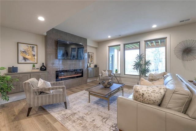 living room featuring a tile fireplace and light hardwood / wood-style floors