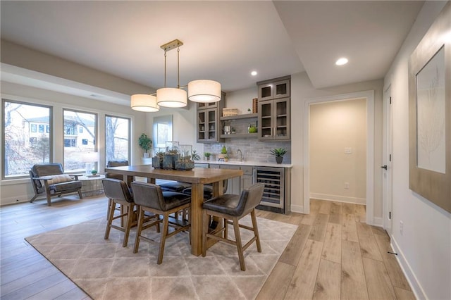 dining area featuring sink, light hardwood / wood-style floors, and beverage cooler