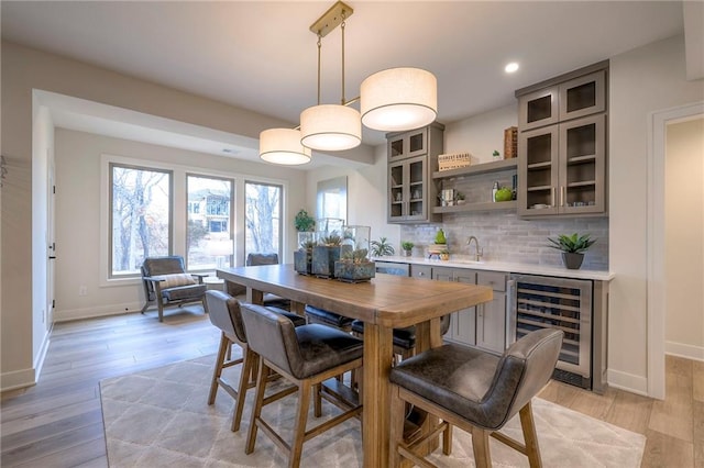 dining area featuring light hardwood / wood-style floors, beverage cooler, and indoor wet bar