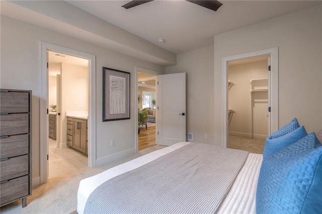 carpeted bedroom with ceiling fan, a walk in closet, ensuite bath, and a closet