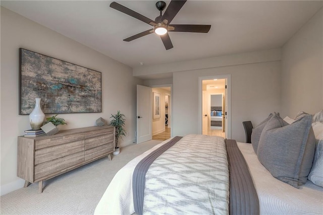 bedroom featuring ceiling fan, light colored carpet, and ensuite bath