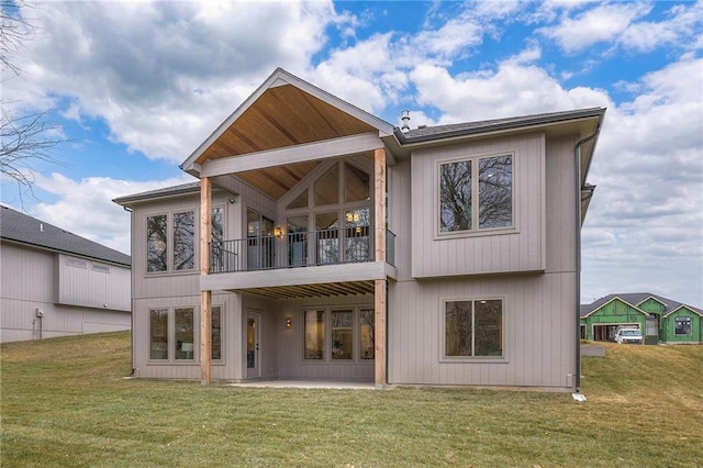 rear view of property with a patio, a balcony, and a lawn