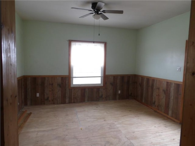 empty room with ceiling fan and wooden walls