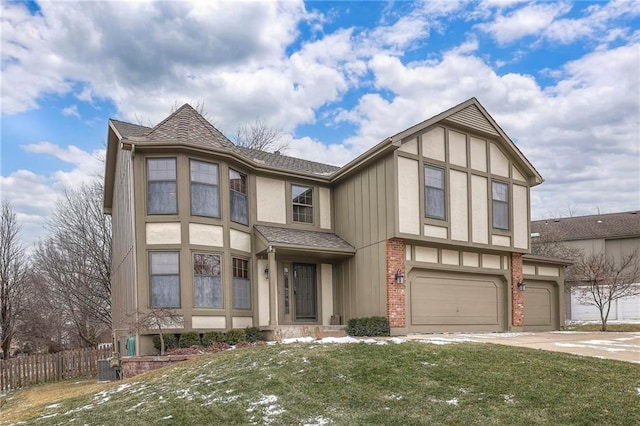 tudor home with an attached garage, brick siding, fence, driveway, and a front lawn