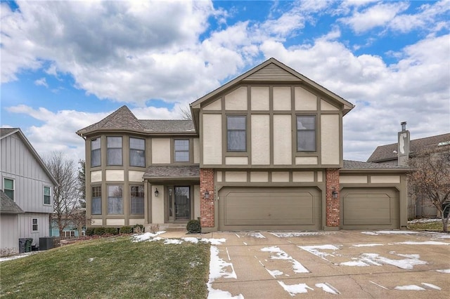 tudor home with an attached garage, central AC, brick siding, stucco siding, and a front yard