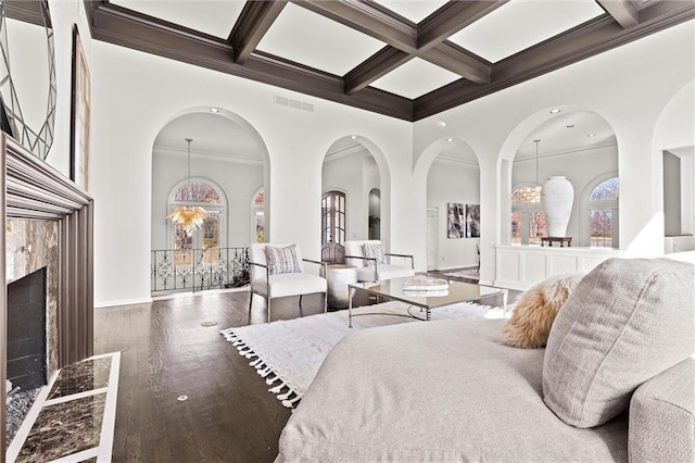 bedroom featuring visible vents, coffered ceiling, a towering ceiling, wood finished floors, and beam ceiling