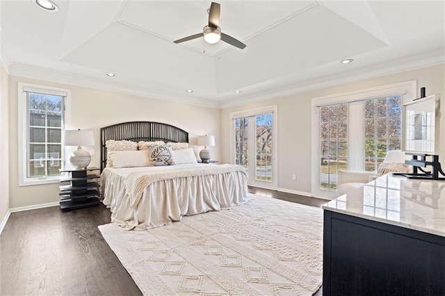 bedroom with multiple windows, a tray ceiling, dark wood-type flooring, and ornamental molding