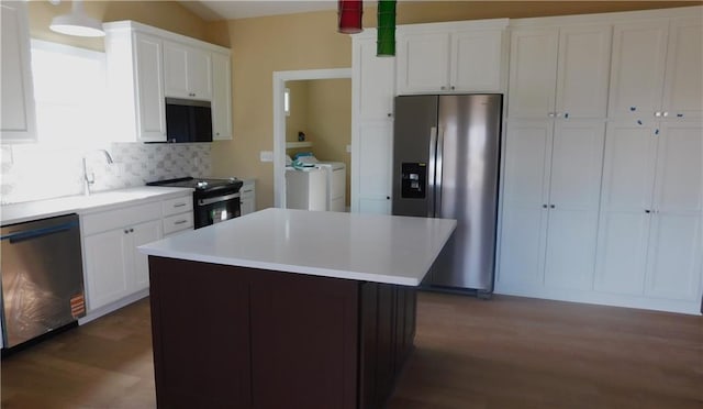 kitchen featuring appliances with stainless steel finishes, light countertops, washing machine and dryer, white cabinetry, and backsplash