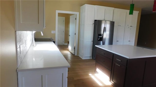 kitchen with light countertops, light wood finished floors, stainless steel refrigerator with ice dispenser, and white cabinetry