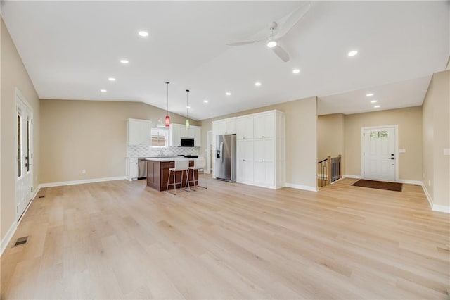 1013 S Main St, Holden, MO 64040 - unfurnished living room with vaulted ceiling, light wood finished floors, visible vents, and baseboards