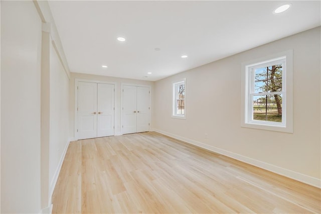 1013 S Main St, Holden, MO 64040 - unfurnished bedroom with light wood-type flooring, multiple closets, baseboards, and multiple windows