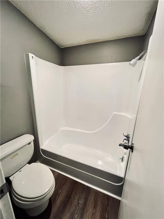 bathroom with shower / tub combination, toilet, hardwood / wood-style floors, and a textured ceiling