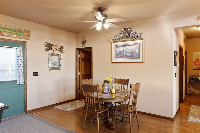 dining room featuring a ceiling fan, baseboards, and wood finished floors