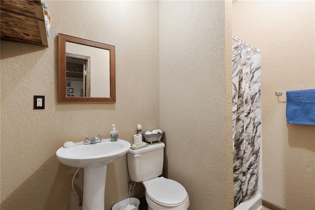 bathroom featuring toilet, a shower with curtain, and a textured wall