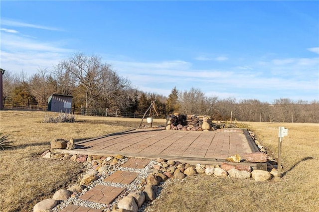 view of yard featuring a patio area, fence, an outdoor structure, and a rural view