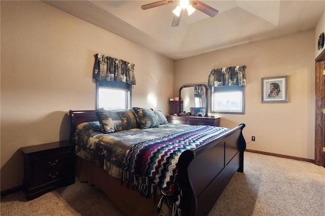 carpeted bedroom with a raised ceiling, ceiling fan, and baseboards