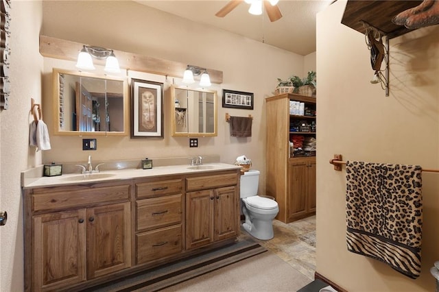 full bathroom featuring toilet, double vanity, a ceiling fan, and a sink