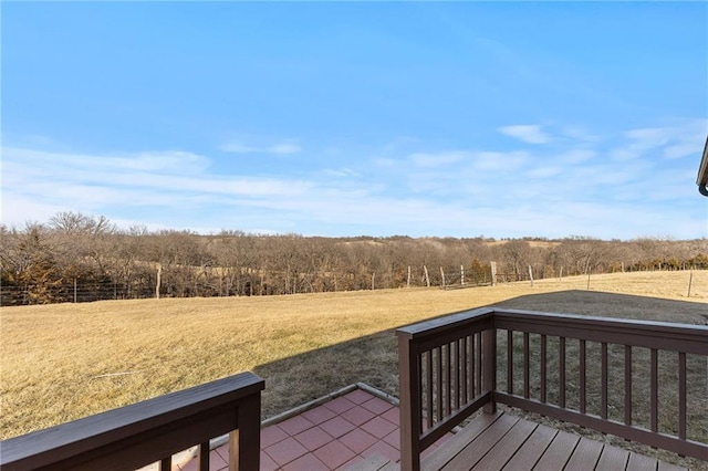 wooden terrace featuring a rural view, a yard, and a view of trees