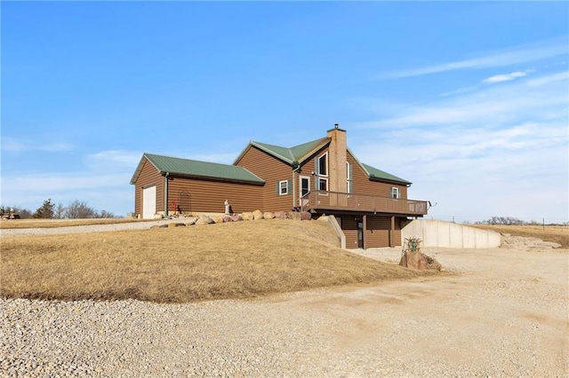 view of front of house with log veneer siding, a chimney, and a wooden deck